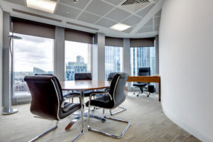 "Small modern office boardroom and meeting room interior with desks, chairs and cityscape view"